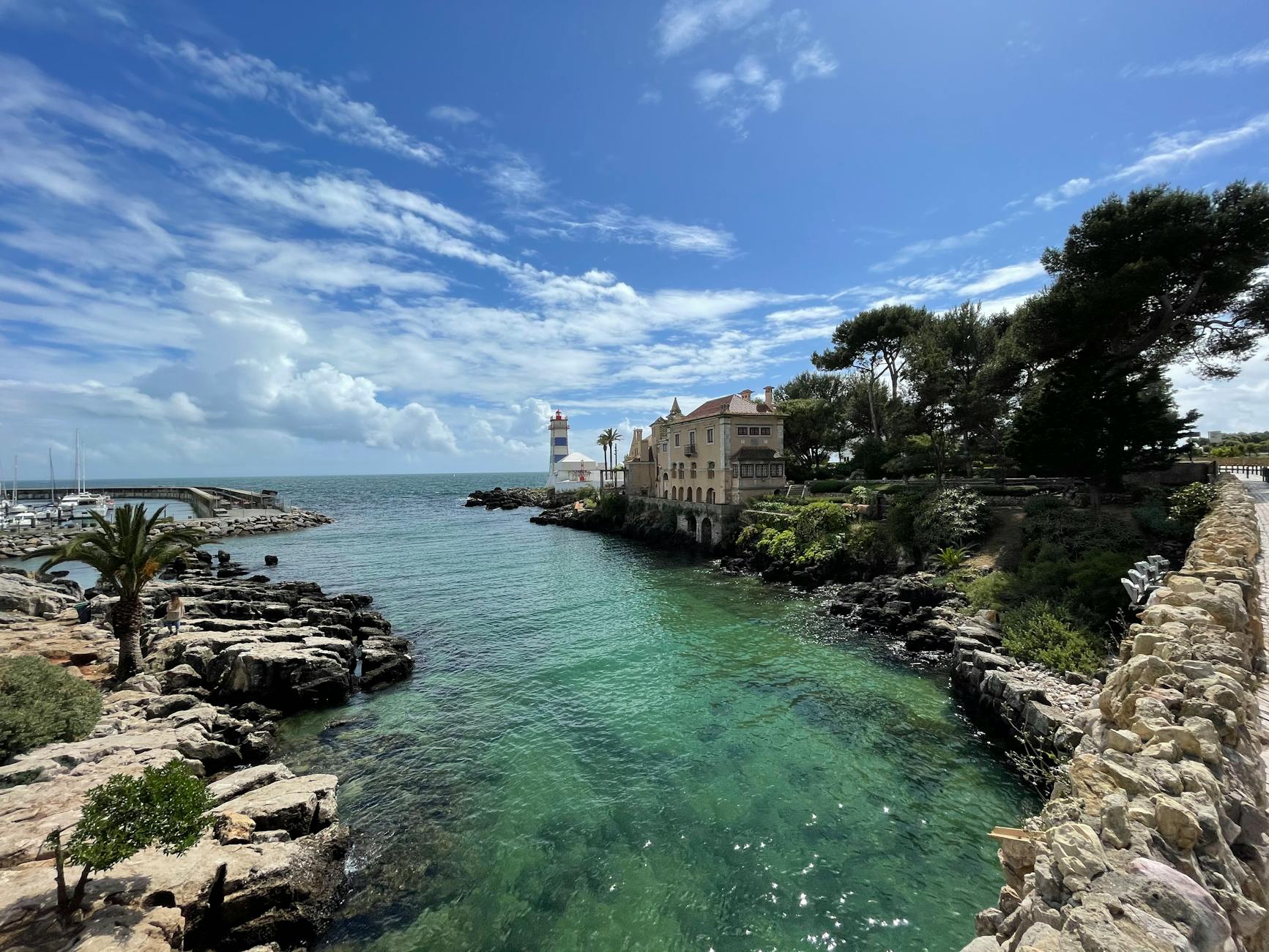 Latarnia Santa Marta w Cascais na tle skał i zieleni nad oceanem