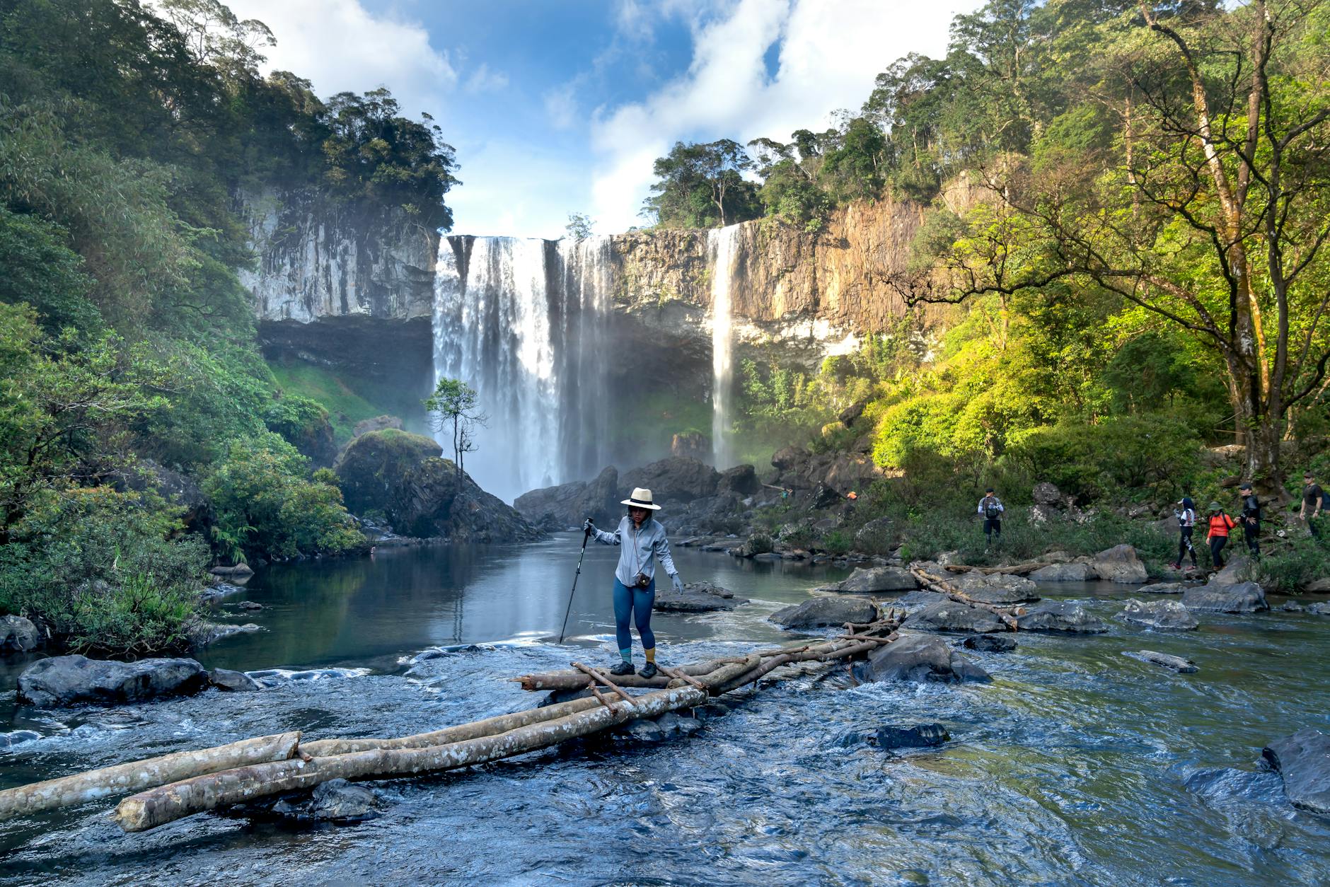 Turyści wspinają się po skałach przy wodospadzie w zielonej dżungli
