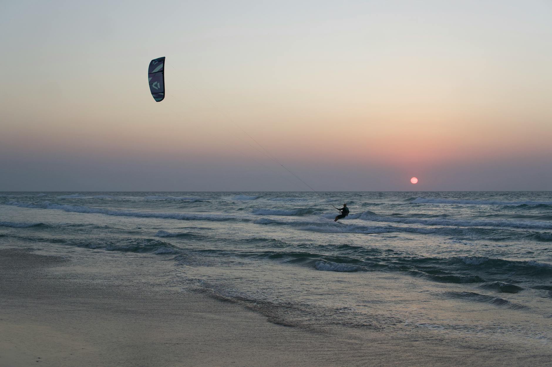 Kitesurfer płynący po oceanie o zachodzie słońca w Mui Ne