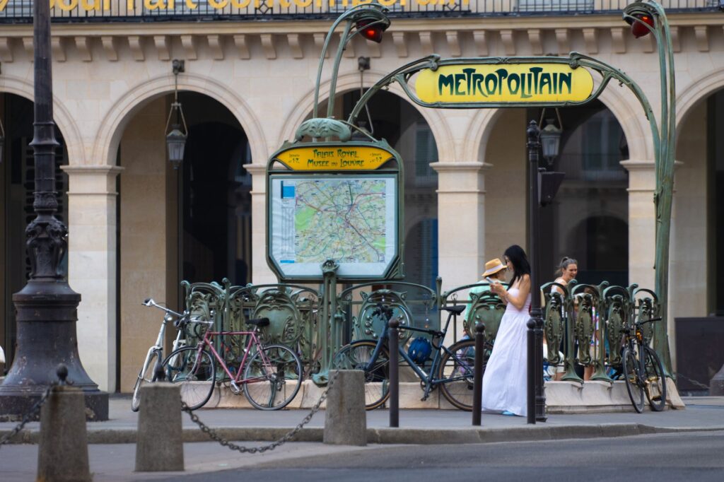 Letni ruch pieszych i rowerów przy wejściu do paryskiego metra